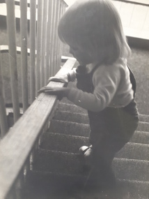 Young boy holding on to railing as he moves downstairs