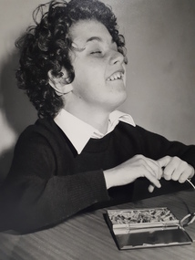 Boy threading pieces on to a cord