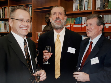Three men holding champagne glasses in a library