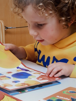 A young child looks at a brightly coloured book