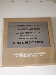 Metal plaque attached to larger board with writing