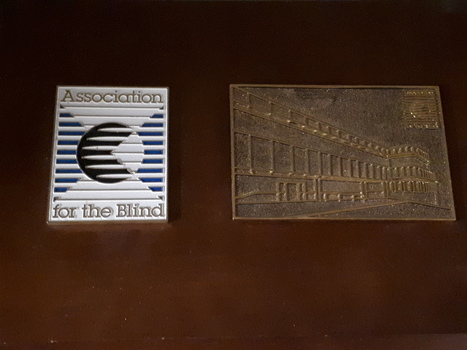 Wooden board with two plaques attached - one with AFB logo and the other a raised line drawing of Kooyong building