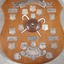 Wooden shield with smaller silver plates engraved with winner names and round wooden ball top in middle with two mini white canes