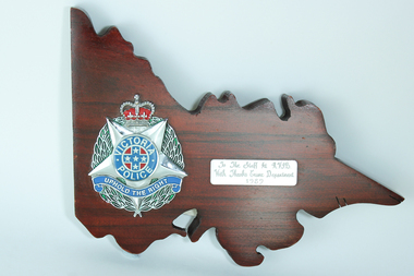 Wooden plaque in shape of Victoria with police emblem on left side