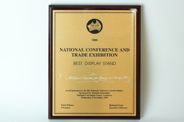 Gold coloured sheet with black writing on wooden rectangle