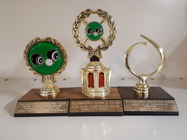Three small trophies consisting of a wood veneer base, nameplate and circular pieces on top, two with filled in discs