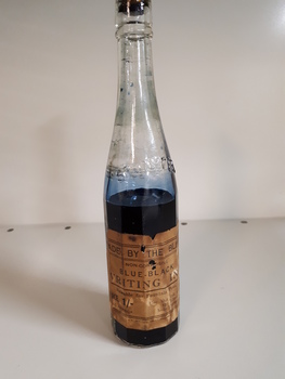 Glass bottle with ink and paper label "Made by the Blind"