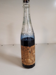 Glass bottle with ink and paper label "Made by the Blind"