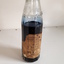 Glass bottle with ink and paper label "Made by the Blind"