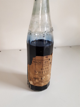 Glass bottle with ink and paper label "Made by the Blind"
