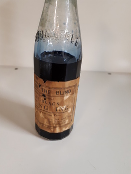 Glass bottle with ink and paper label "Made by the Blind"