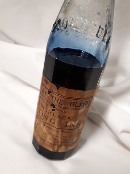 Glass bottle with ink and paper label "Made by the Blind"