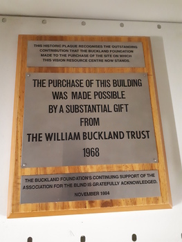 Three metal plaques attached to wooden board