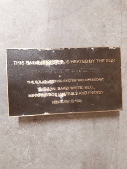 Brown plaque with gold coloured writing and Braille tape