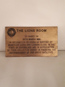 Gold coloured plaque with brown writing inscribed and Lions logo in top left hand corner