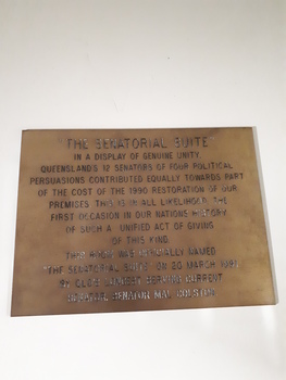 Gold coloured plaque with brown writing inscribed.
