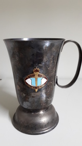 Tarnished silver mug with enamel badge