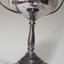 Rear view of silver cup with two handles on black base with years and winner engraved