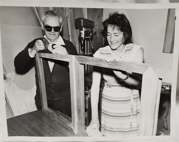 Two people working on a wooden frame
