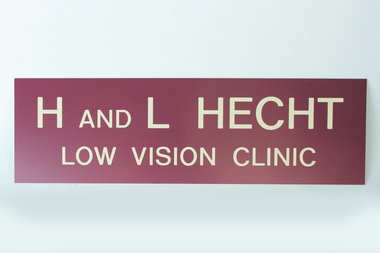 Cream writing engraved on maroon coloured sign