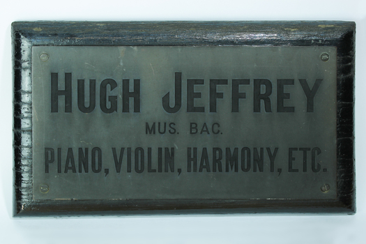Metal rectangular plaque attached to black wood