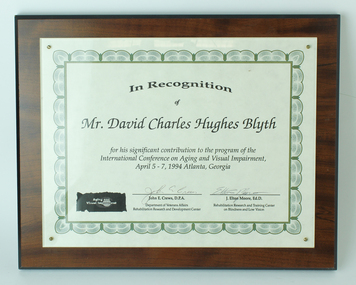 Paper certificate laminated on to wooden board.