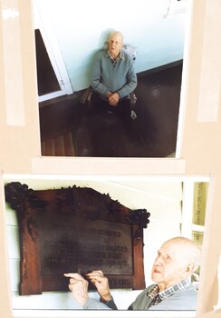 Elderly man in chair beneath plaque on porch.  Elderly man touching wooden plaque.