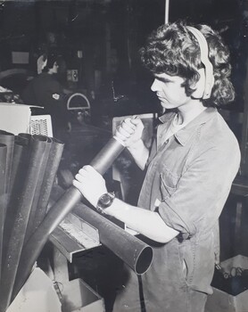 Male handles metal pipes in a workshop.