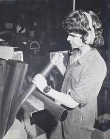 Male handles metal pipes in a workshop.