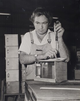 Male using a tool to attach a lid to a box