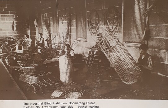 Men in long sleeved shirts and vests weave cane into baskets and other things in a workshop