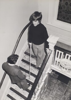 A person with a white cane descends the narrow staircase at RVIB