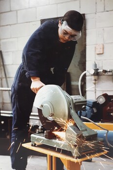 Young man using a bandsaw in a workshop 