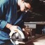 Man in blue coveralls uses a circular saw on a piece of wood