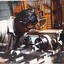 A man in beige coveralls uses a machine in a workshop