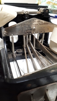 Black metal typewriter which has seven hinges and a small reel of paper