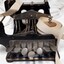 Black metal typewriter which has seven keys and a small reel of paper