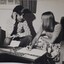 Man speaking to woman in a lounge room with paper forms in front of her