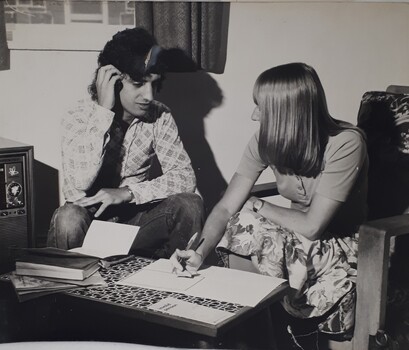 Man speaking to woman in a lounge room with paper forms in front of her