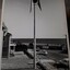 Side view of tall pole topped with a large globe surrounded by metal pieces, overlooking the foreshore at Brighton during the day.