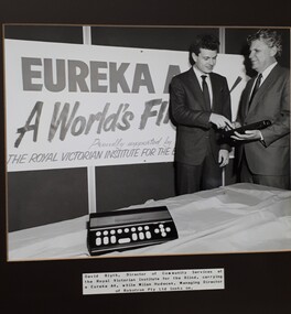 One man points to a computer held by another