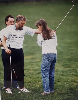 Teacher steadies the raised golf club of a student