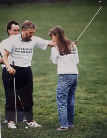 Teacher steadies the raised golf club of a student
