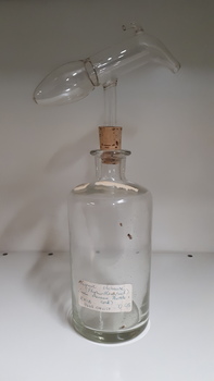 Glass bottle with cork stopper and glass measuring device attached above