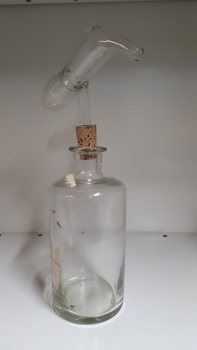 Glass bottle with cork stopper and glass measuring device attached above
