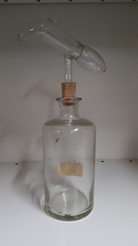 Glass bottle with cork stopper and glass measuring device attached above