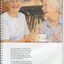 Two older woman chat in a day centre, one holding out a cup of tea to another