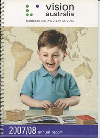 Picture of small boy smiling as he touches tactile boxes which lie next to a Brailled picture book