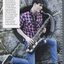 Campbell Ball playing a saxophone against a concrete wall