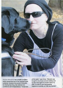 A young woman wearing black glasses and hat and her Seeing Eye Dog Warwick